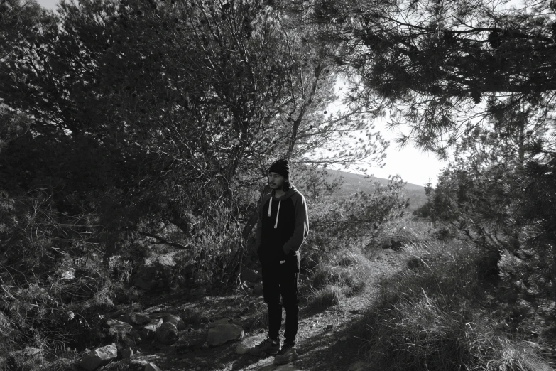 man standing on dirt trail next to trees