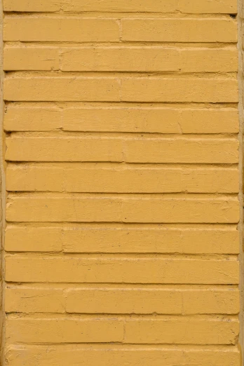 a yellow wall with a brown street sign