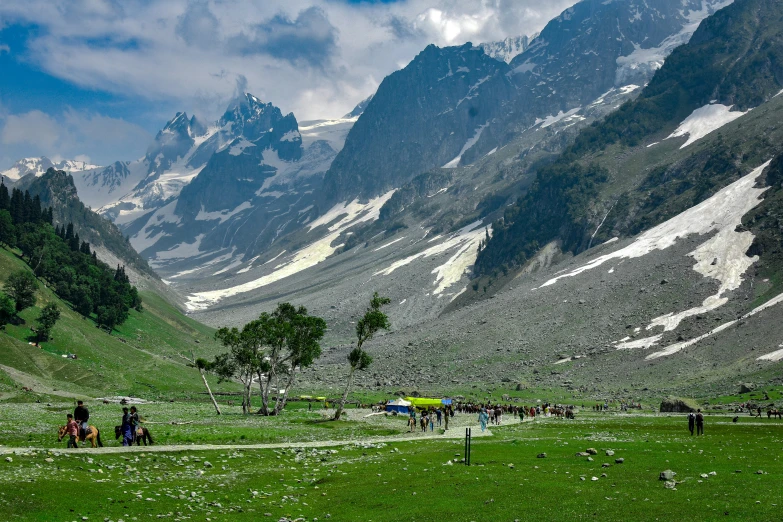 a group of people walking on grass near mountains