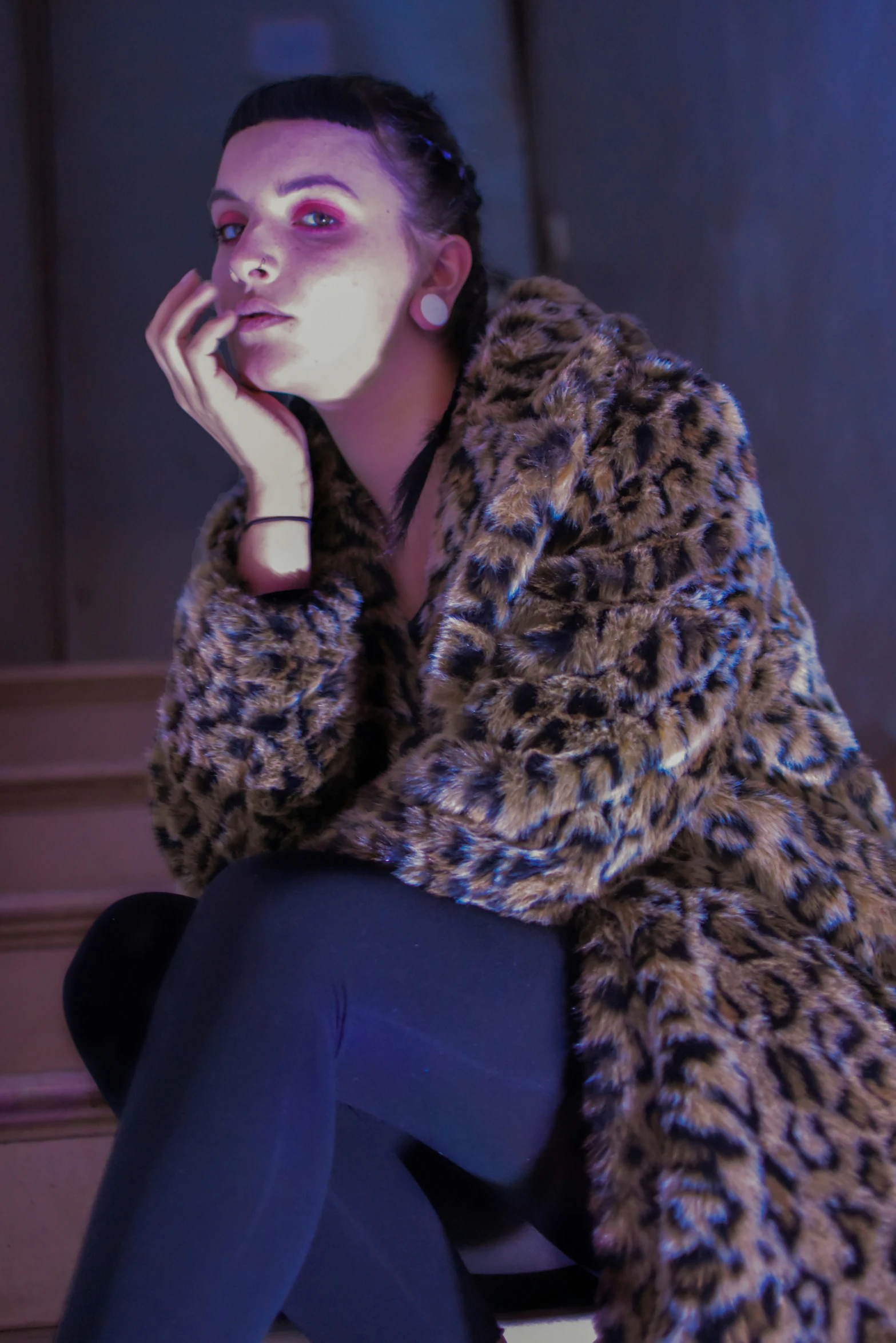 a woman sits on a step wearing a leopard coat