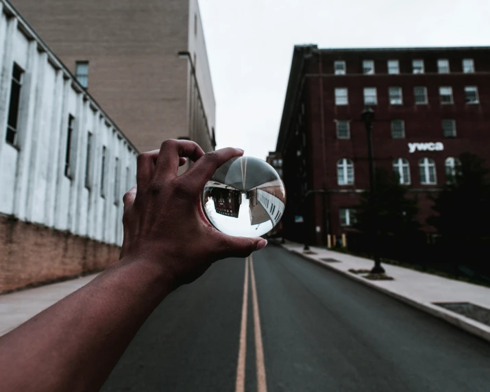 someone holding their hand up with their reflection in a ball