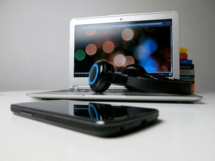 a black cellphone sitting in front of a laptop on top of a desk