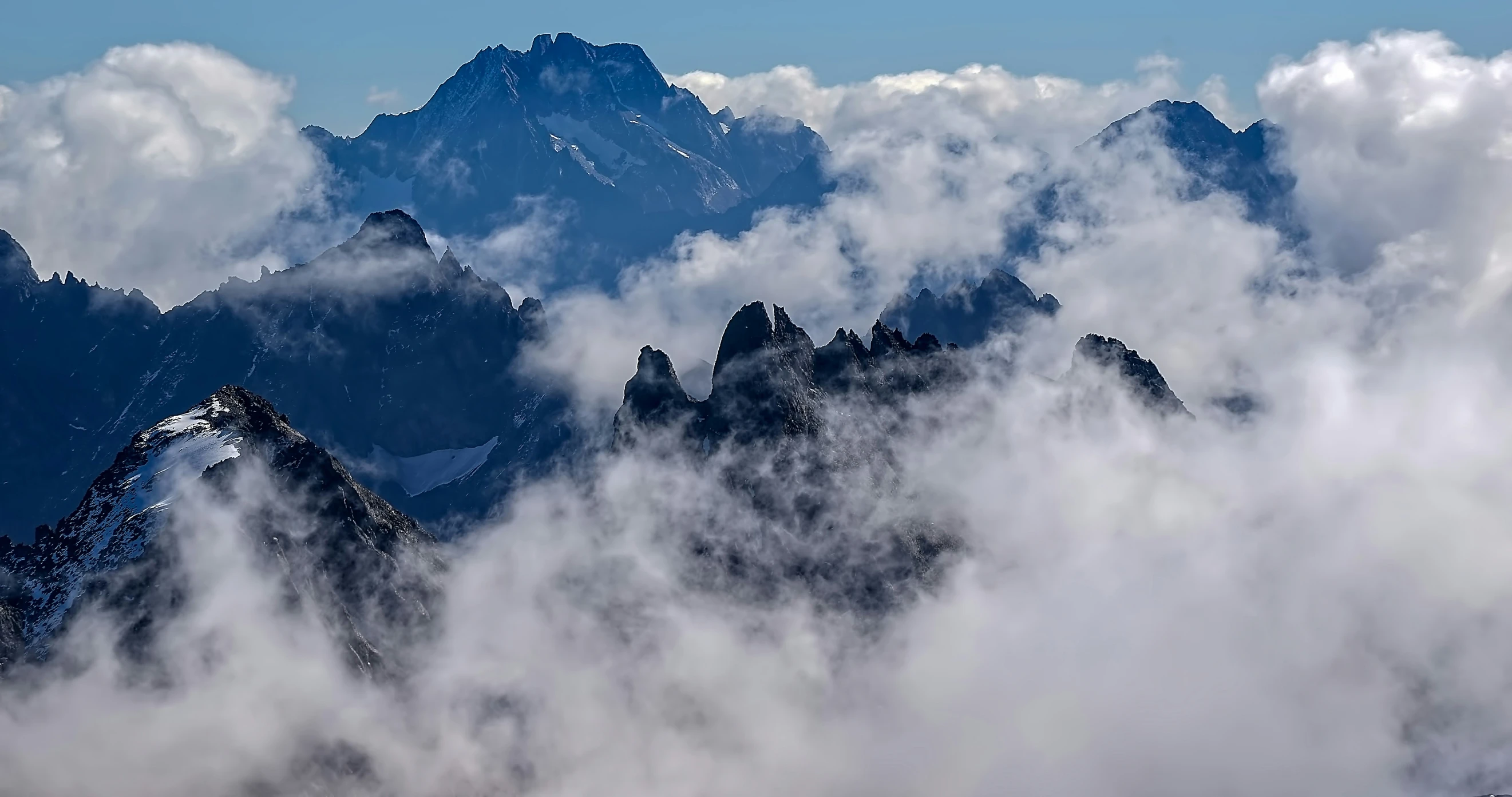 the mountains are covered in clouds and some snow