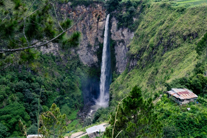 a large waterfall near a hill side with trees