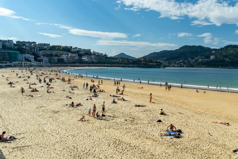 many people are standing and laying on the beach