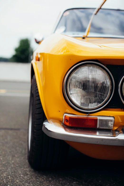 a yellow classic sports car sitting on the street