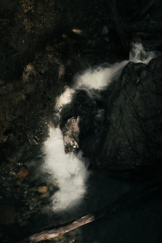 a stream that runs over rocks is surrounded by dark, shadowy rock formations