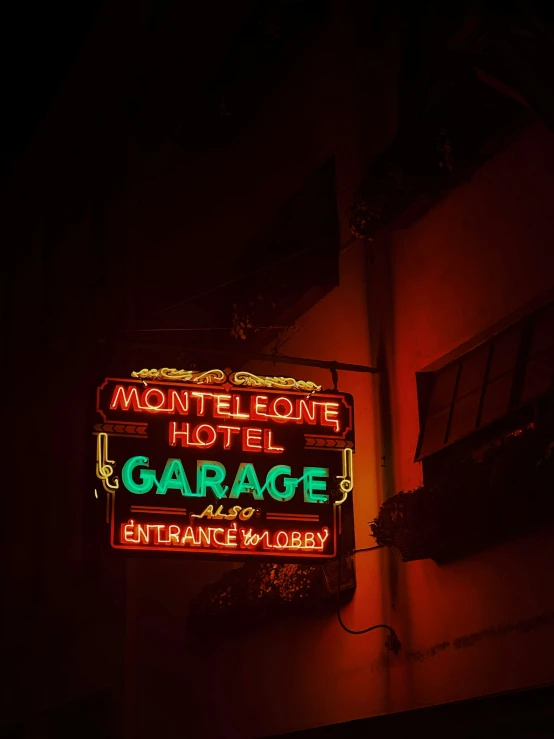 an illuminated motel sign hanging on the side of a building