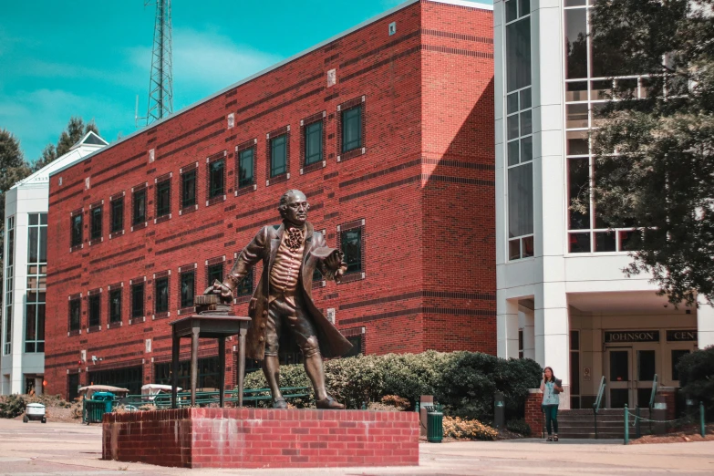 a statue of a man with a jacket on in front of an industrial building