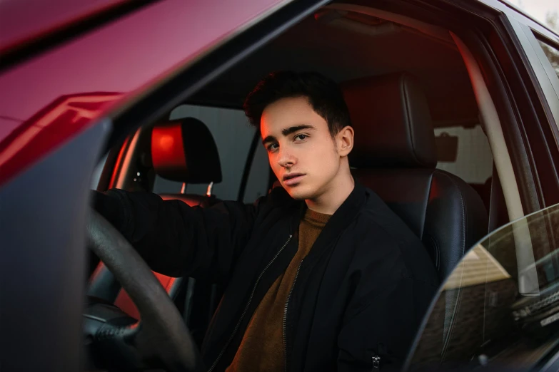 a young man sitting in the drivers seat of a car