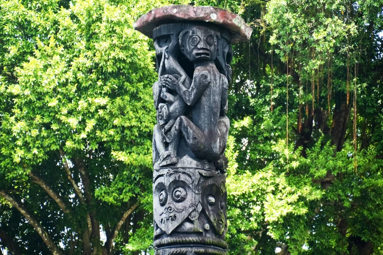 an outdoor sculpture made of wood is standing in front of trees