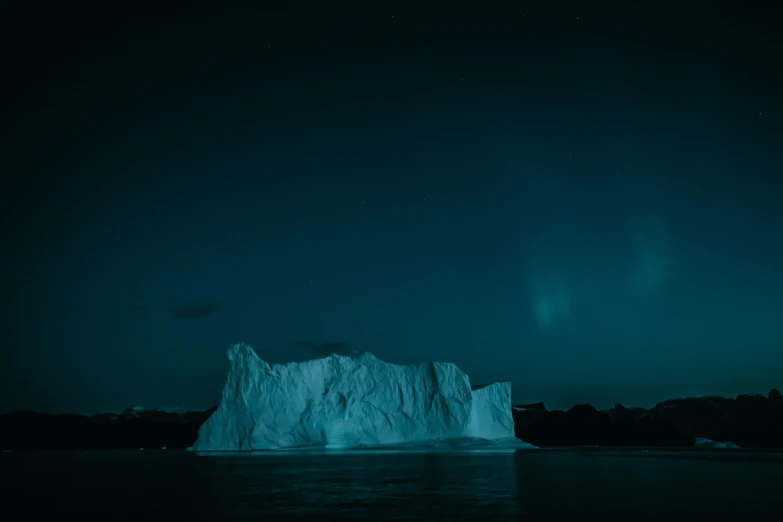 an iceberg floats in the ocean at night