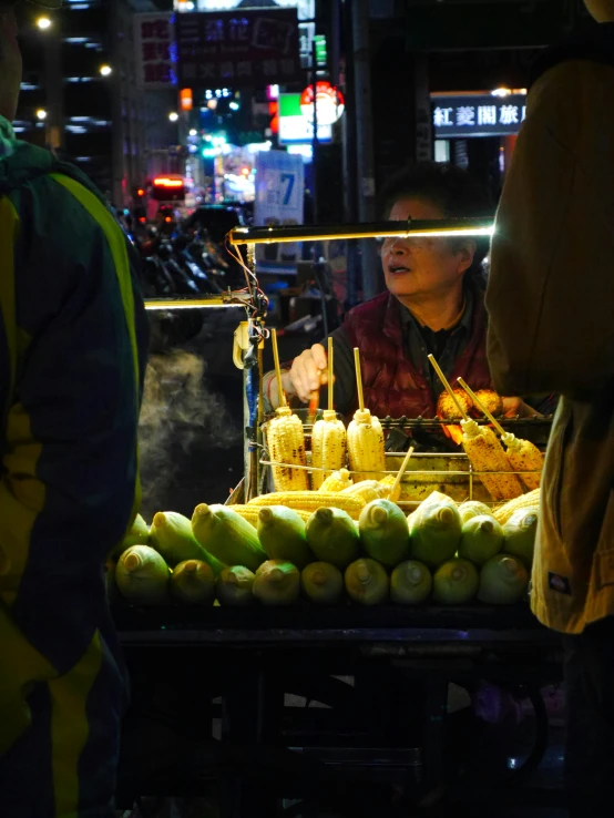 people in an asian area are looking at fruit at night