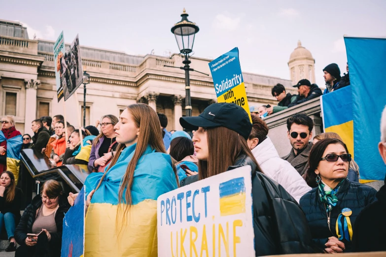 women in blue and yellow are holding signs