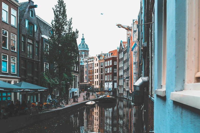 a narrow city street lined with buildings, trees, and water