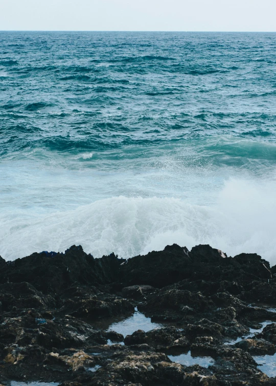 some sea foamy water on rocks and an orange frisbee