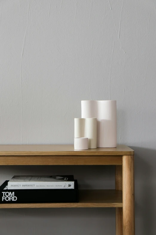 an open book on a bookshelf beside some white coffee cups