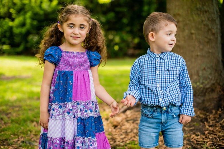 two young children standing together on the grass