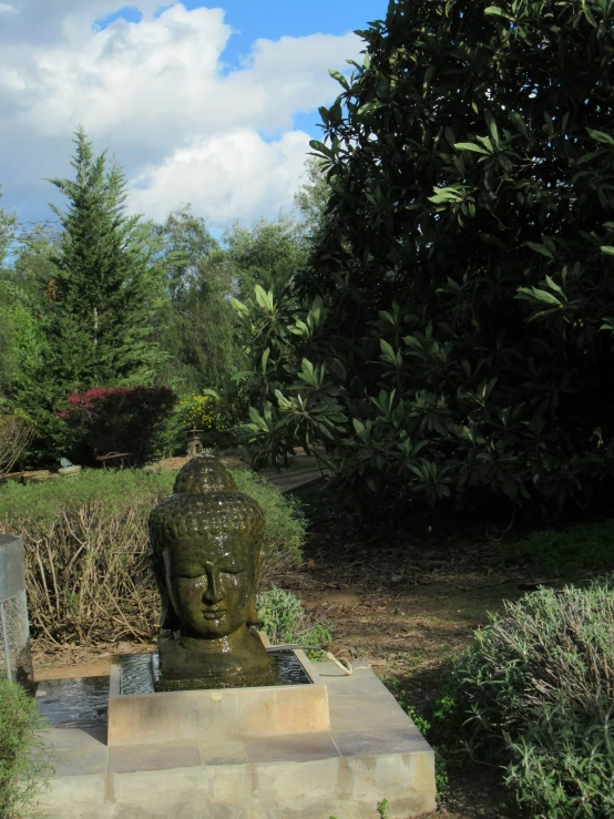 a small stone buddha sits on a ledge in the park