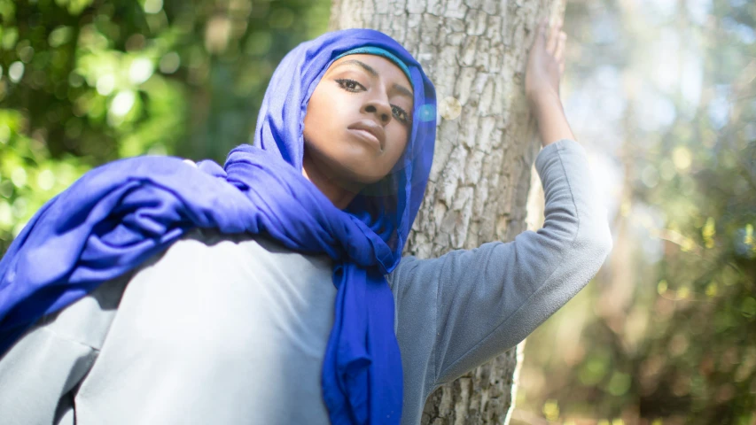 an image of woman wearing head scarves standing next to tree