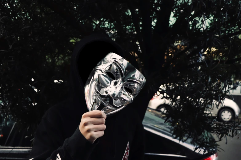 a man is holding up a mask on his face