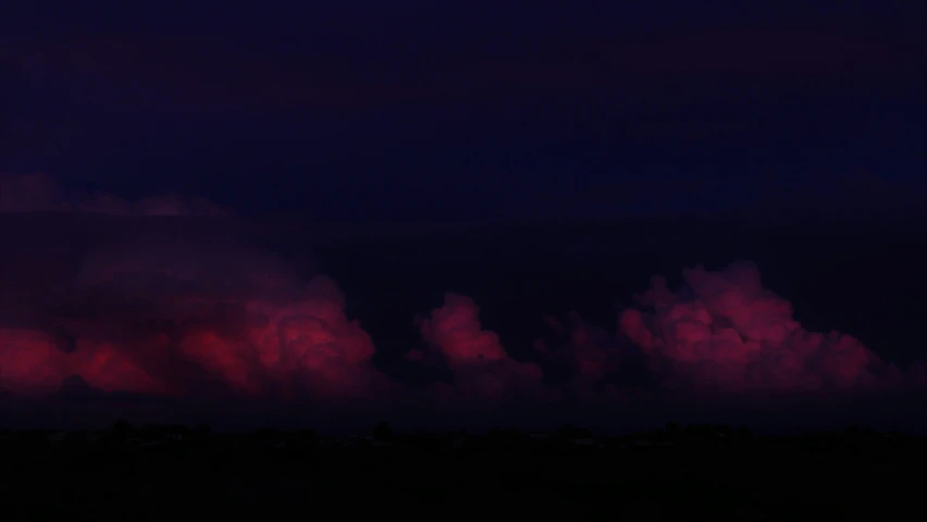 pink clouds in a dark night sky with a white plane