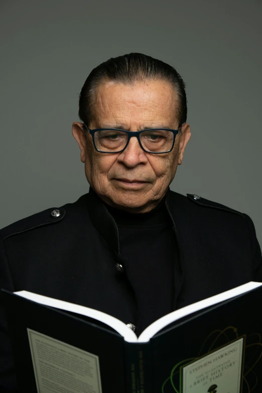 a man in glasses and a suit jacket reading a book