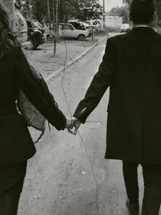 a couple holding hands walking down a street