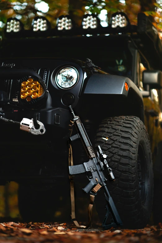 a jeep with its lights on sits in the woods