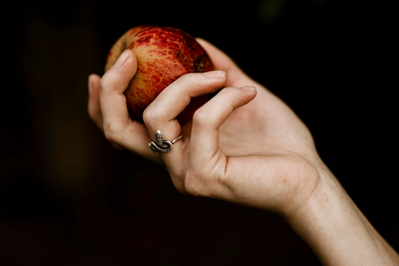 a person's hand holding an apple with a diamond ring