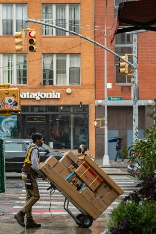 a man hing a dolly with boxes on it through the city