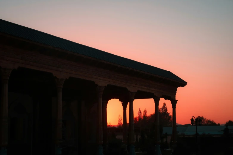 the sun sets behind some ornate arches