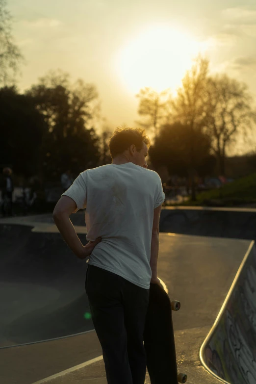 a man looking at the sun with his skate board