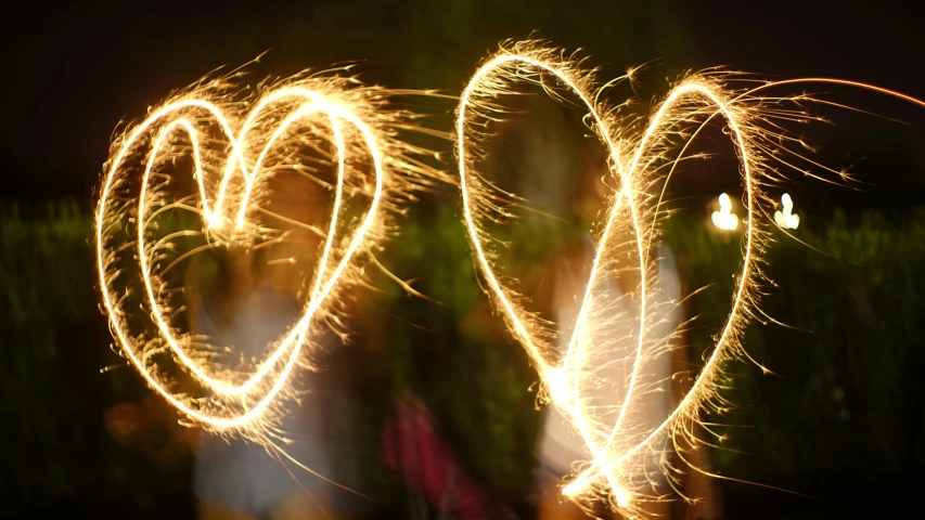 two hearts shaped with sparklers at night