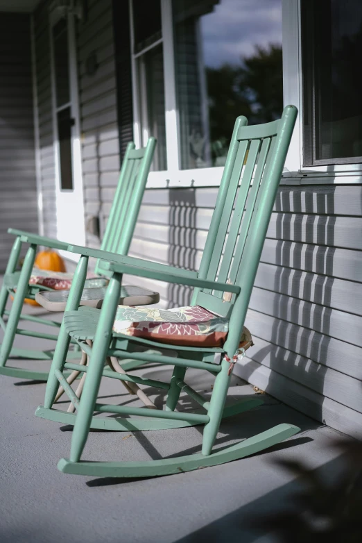 two rocking chairs with cushions on a porch