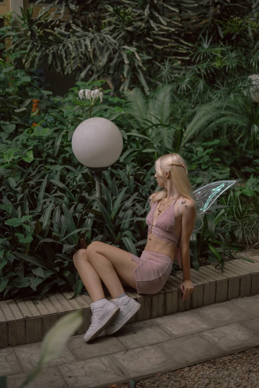 a woman with  is sitting on a bench by some plants