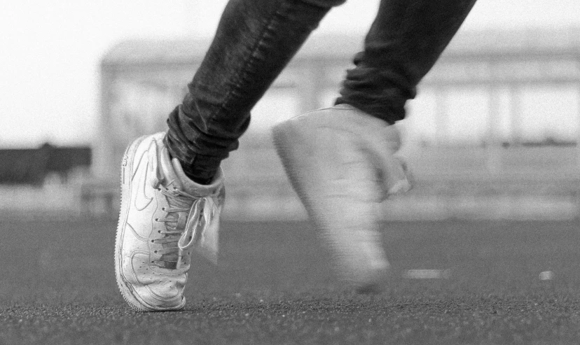 a black and white pograph of someones legs with tennis shoes