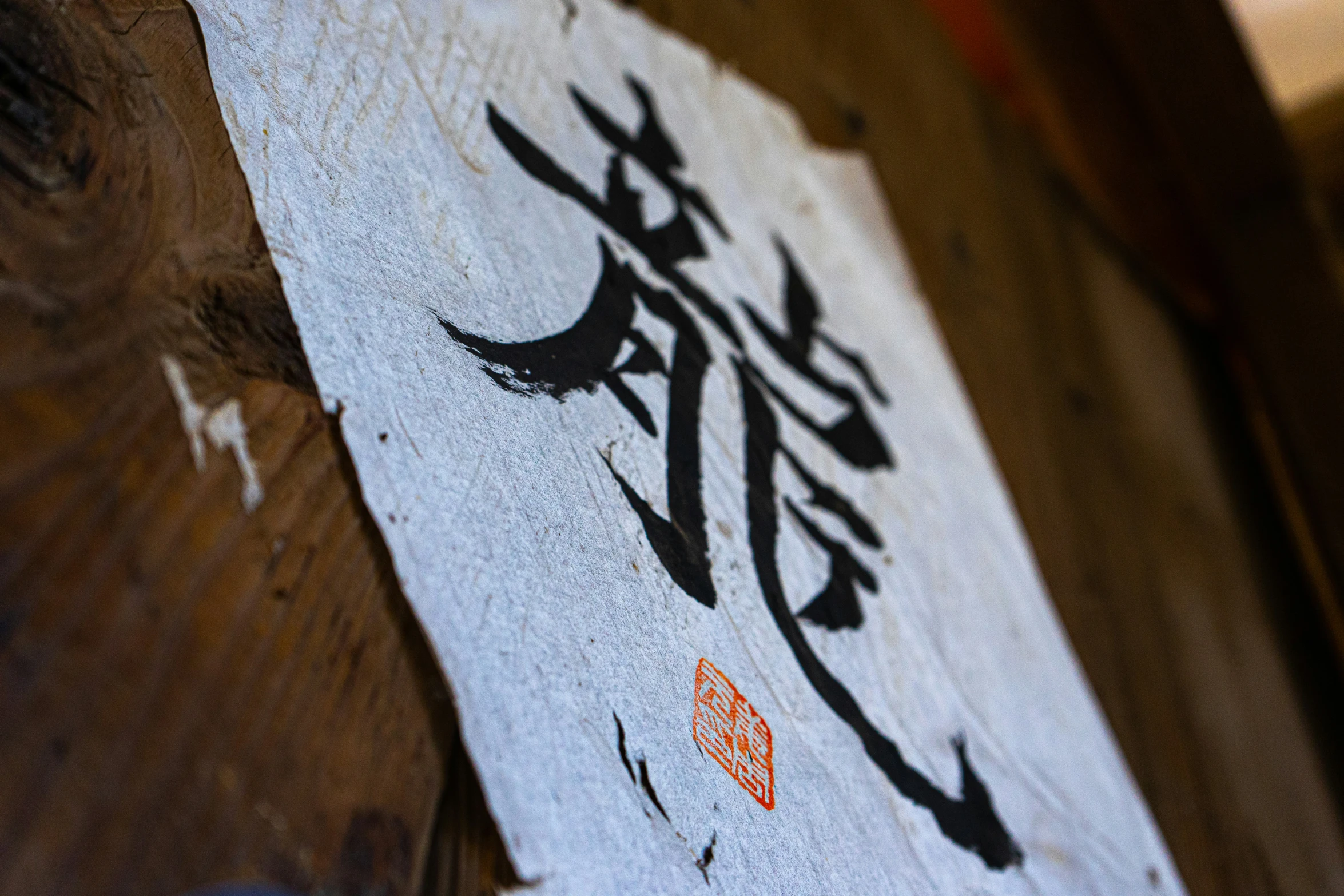 a white wooden sign with calligraphy painted onto it