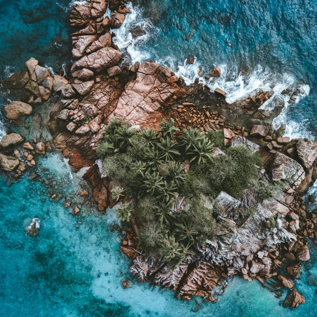 an aerial view of a shoreline that has blue water and some rocks