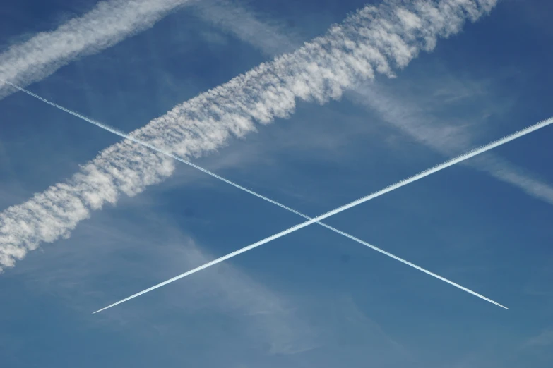 two airplanes are in the sky with contrails trailing them