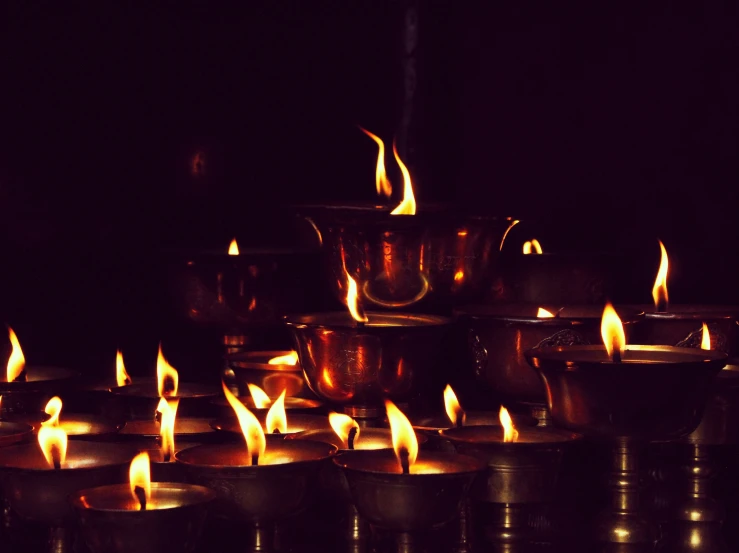 a group of lit candles in front of dark background