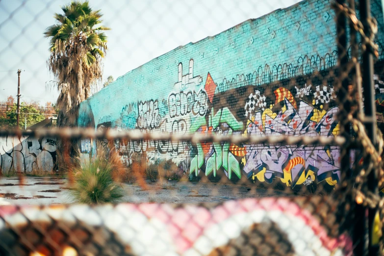 a graffiti painted wall behind a chain link fence