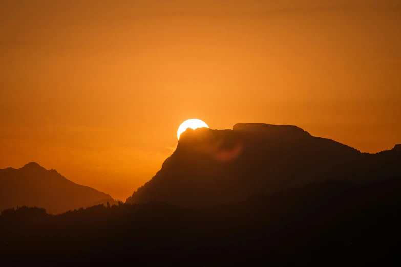 the sun rising over mountains during sunset