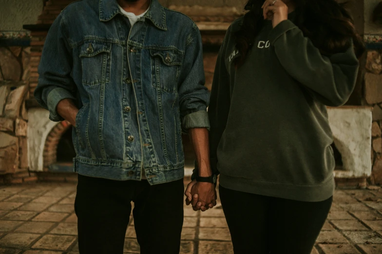 a young man and woman are standing by the fireplace