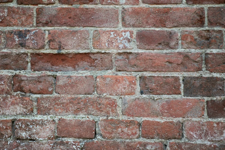 the top portion of a brick wall with many white patches