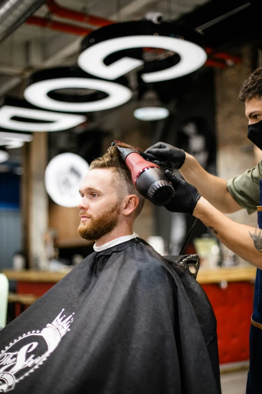 a man getting his hair cut while another person stands nearby