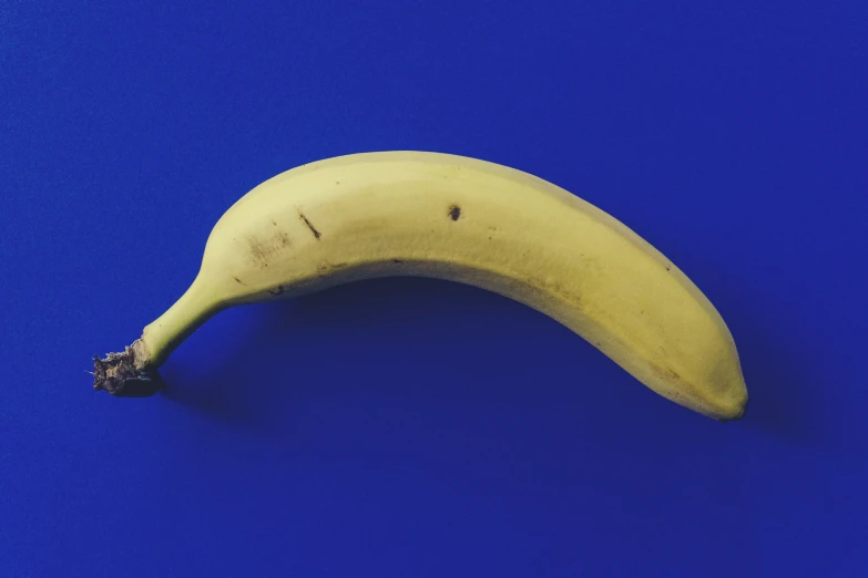 a yellow banana is lying on a blue table