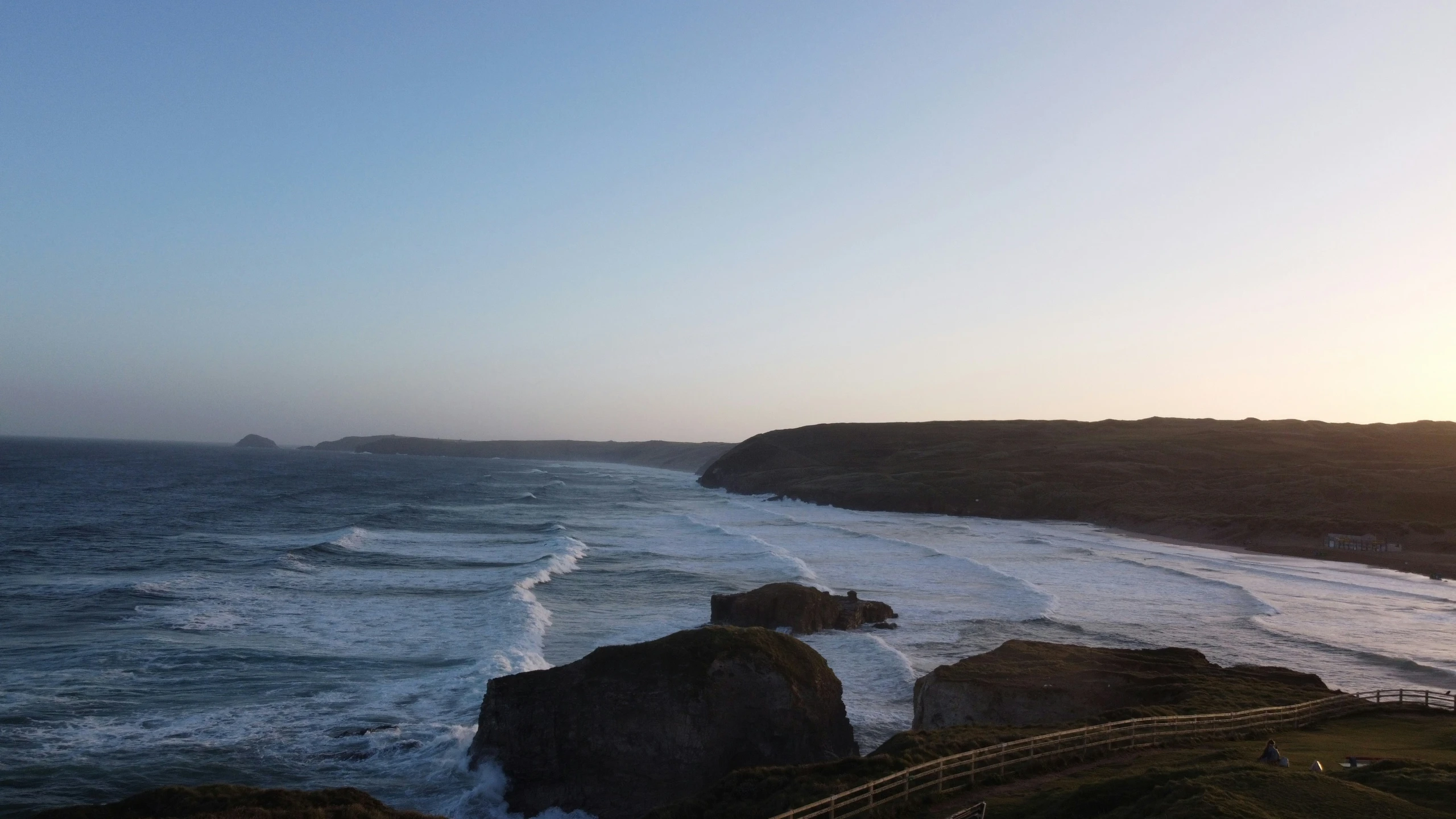 waves come in at the edge of a cliff with a walkway