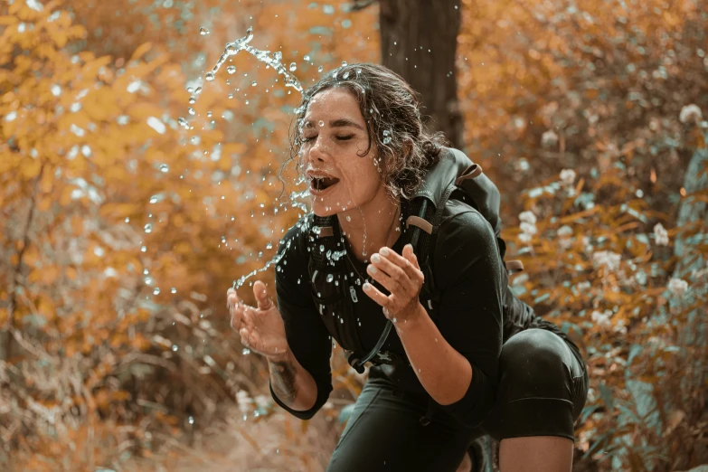 a girl with a back pack splashing water on her face
