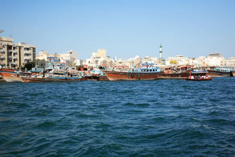 many boats sitting at the edge of the ocean in front of tall buildings